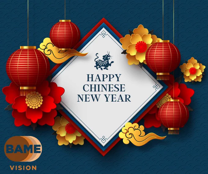 An Image of a blue background with four red and gold glowing lanterns which are hanging. They encircle a white diamond, with a red and black intricate outer border. At the top of the diamond,there is an image of a small dragon. Beneath this, the words 'Happy Chinese New Year' are elegantly written in navy blue. Surrounding the diamond are two yellow and two red origami flowers. In the bottom left corner, the BAME Vision logo