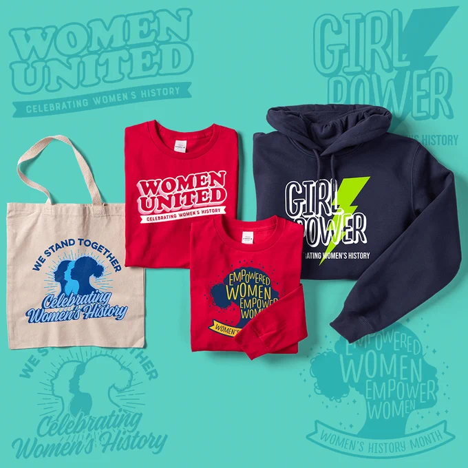 Laydown of a tote bag, t-shirts, and hoodie with designs meant to empower and celebrate women.