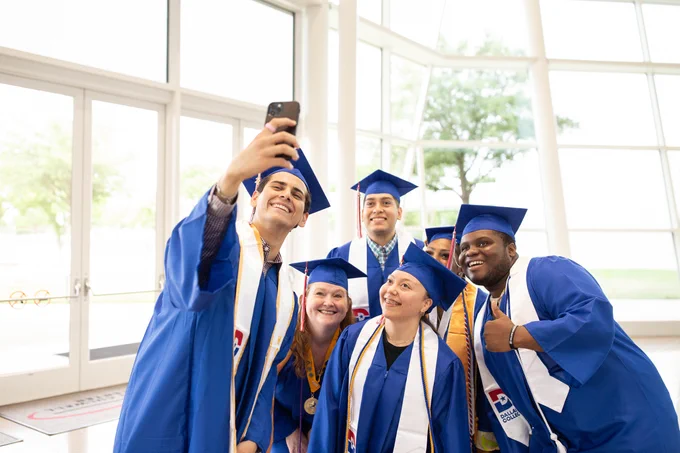 Photo of dallas college graduates taking a group selfie. 