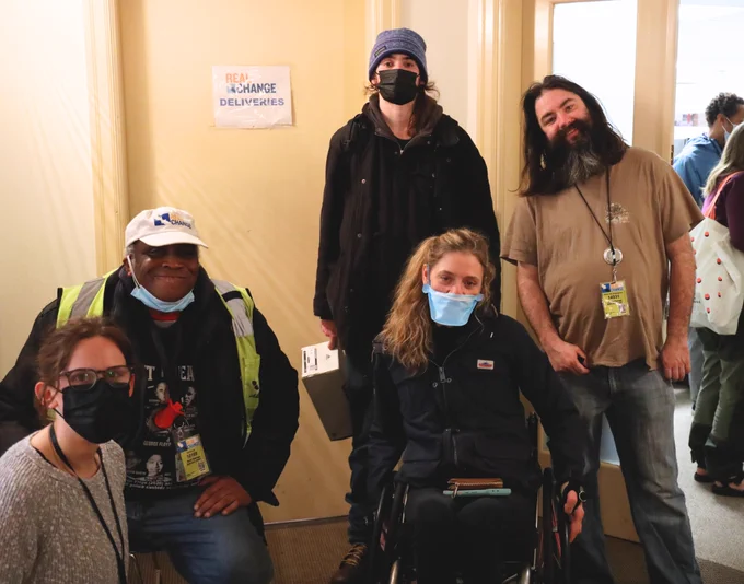 Cecelia, an organizer from the Disability Mobility Initiative, poses with Real Change vendors Addis, Noah and Erick as well as Real Change Policy and Campaigns Associate Camille