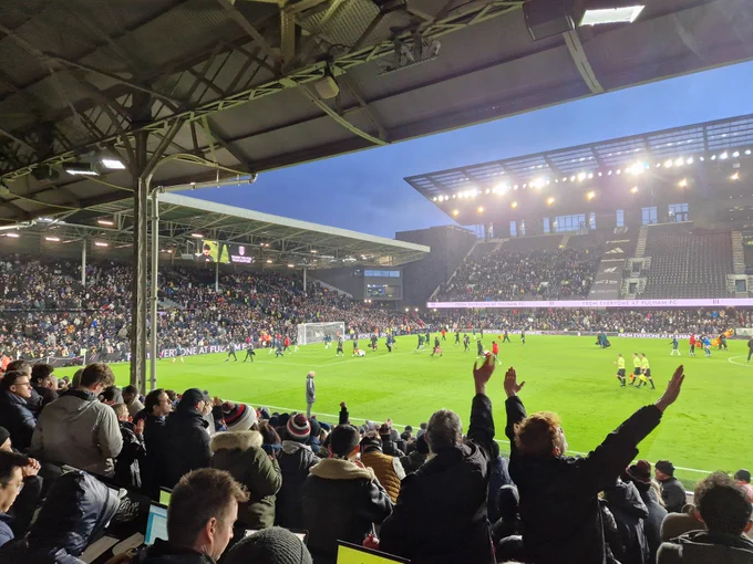 Photo of the Craven cottage pitch under floodlights and stands with fans applauding the players as they walk off