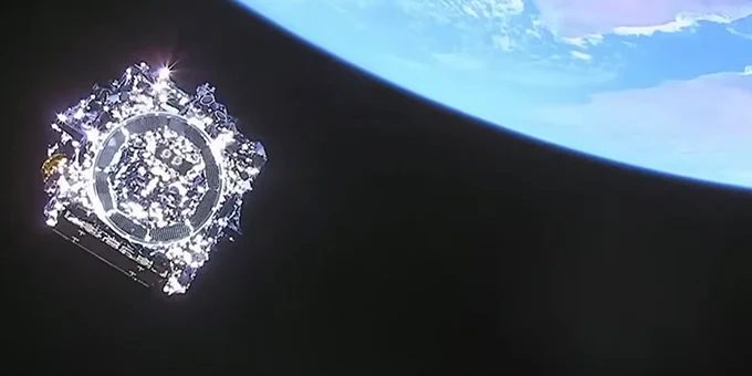  Silver spacecraft in space with Earth above.