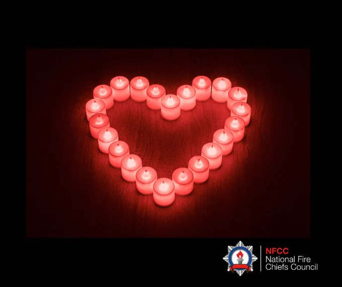 Graphic:  Photo  of Lit LED candles in a heart shape on a black background.