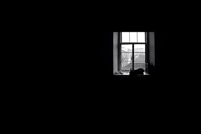 Una escena completamente oscura con una ventana en la que entra luz.