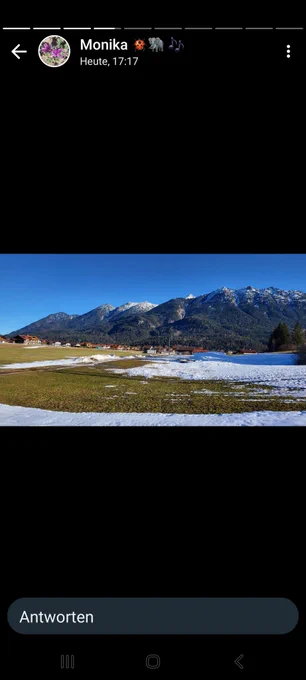 Eine Landschaft im Landkreis Garmisch-Partenkirchen im Januar 2024. Eher grüne Wiesen, Reste von Schnee im schattigen Bereich. Ansonsten Kunstschnee zu einer Loipe geformt 