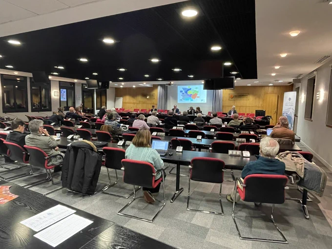 Salle de conférence, on voit les participants de dos, ils assistent à une présentation sur l’air et la santé.