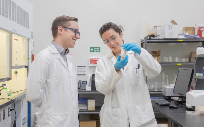 Zac Young and Kate Breberina smiling and looking at water that has been treated inside the H2nanO lab