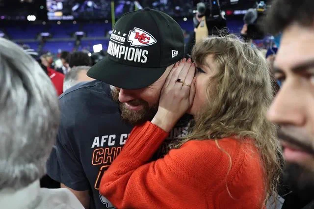 Taylor Swift whispering something to Travis Kelce
