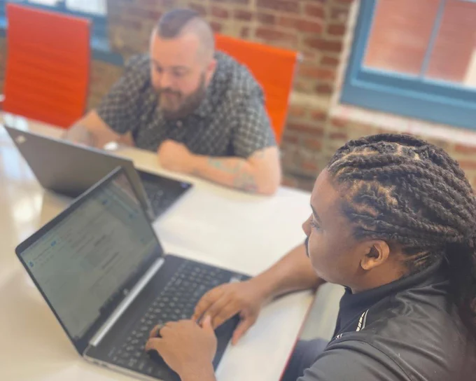 A man and child sitting at a table with a laptop.