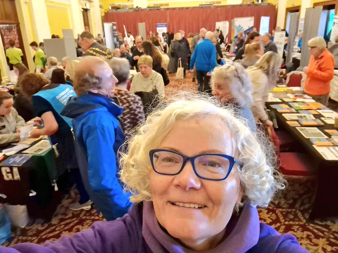 White woman at a community event with people and stalls behind 