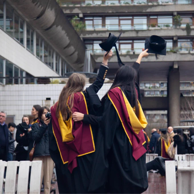 A photo of a student posing for a photo in their graduation outfit 