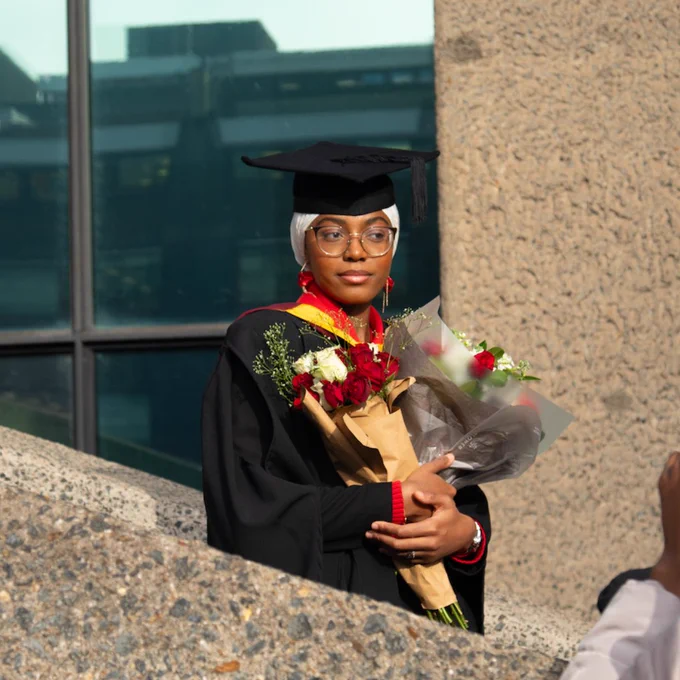 A photo of a student posing for a photo in their graduation outfit