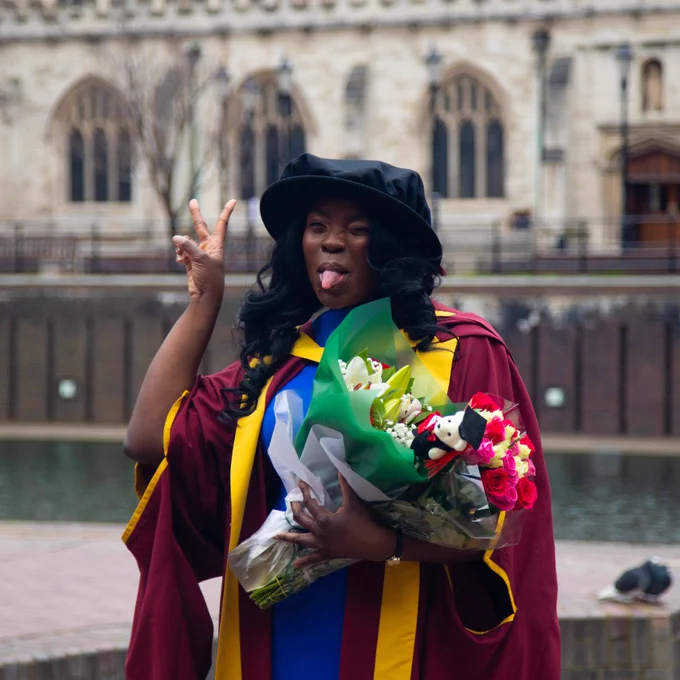 A photo of a student posing for a photo in their graduation outfit