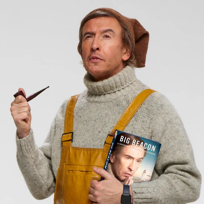 Partridge clasps copy of book between fingers and palm of left hand and clutches bowl of smoking pipe between first fingers and thumb of right hand. Facial expression suggests wistful contemplation of storm brewing in distance (not pictured). Face skin is browned through outdoor work but looks cleansed and moisturised because is. Hat, watch, knitwear and chest waders courtesy of Cromer Seafood Museum