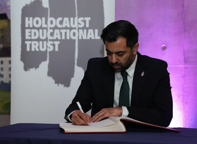 First Minister Humza Yousaf signing the Holocaust Book of Commitment with a banner that says Holocaust Educational Trust
