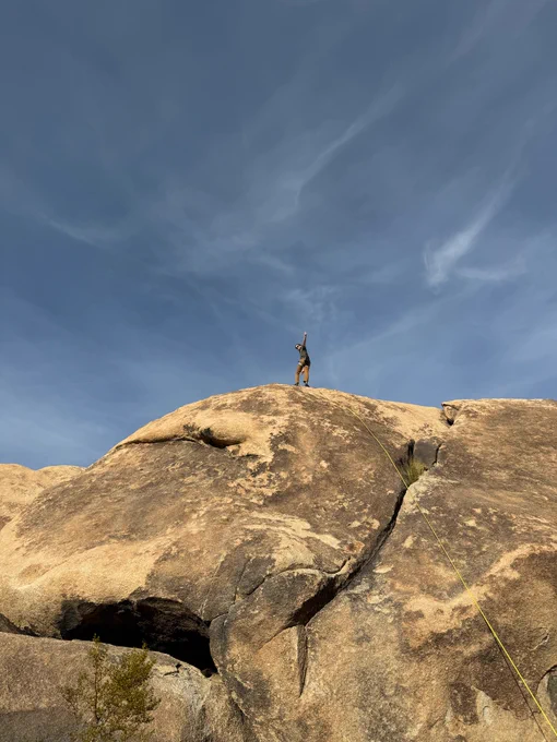 Me on top of a 40-foot granite rock giving a thumbs up, ready to lower on a climbing rope