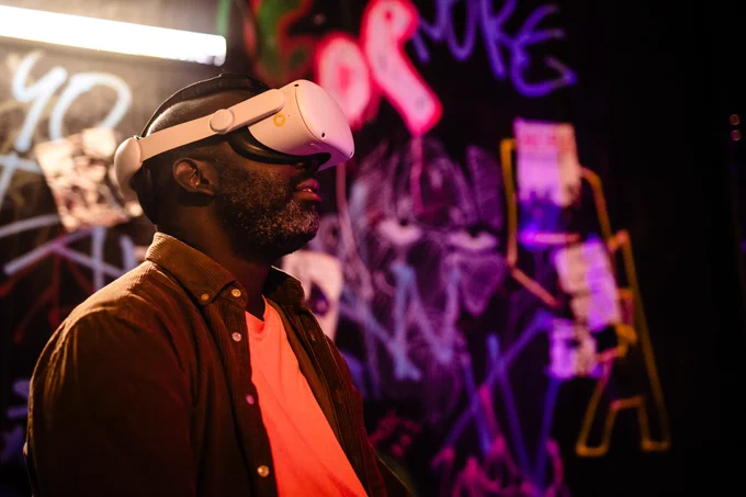 A man wearing VR goggles in a room with walls covered in brightly coloured neon paint