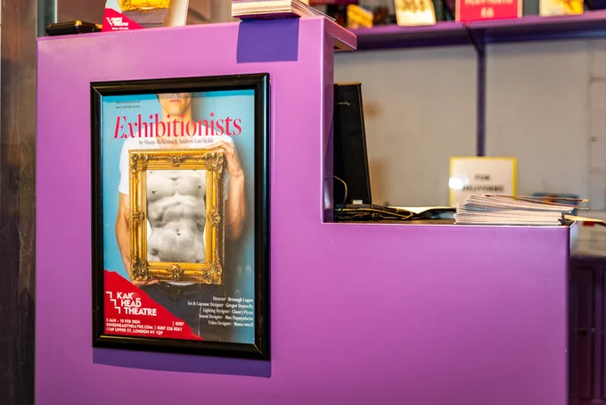 A poster for Exhibitionists framed against the purple frontage of the box office of the King's Head Theatre. Photo by Jake Bush