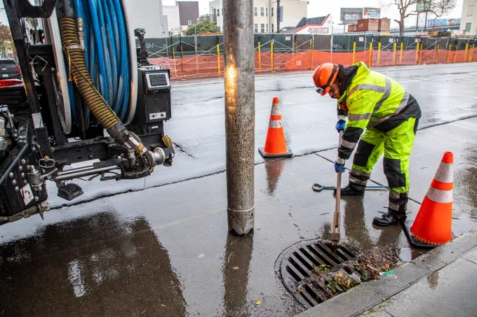 SFPUC Crew member clearing out a storm drain.
