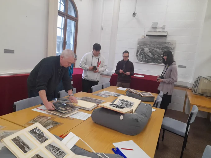 Weston College students examine photos and archives displayed on a table. 