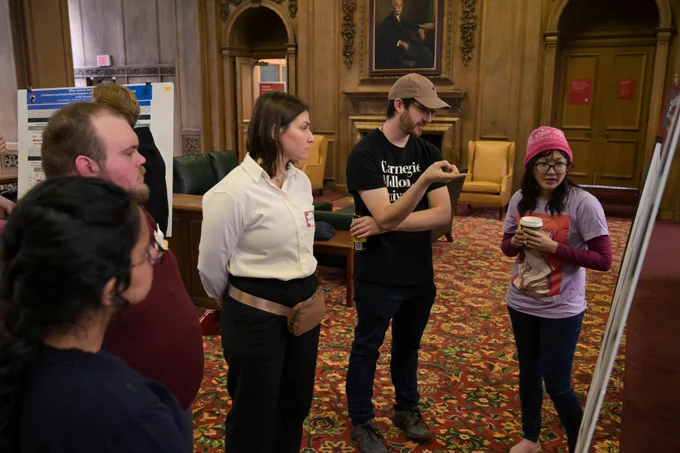A group of five people discuses a research poster.