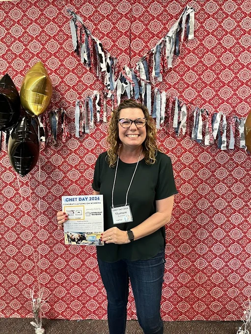 A smiling teacher holding a Ditch That Textbook course certificate