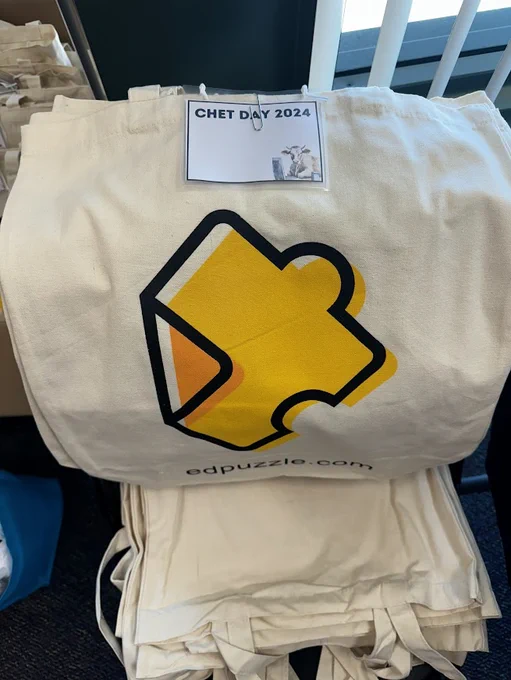 stack of ed puzzle ivory canvas bags with a yellow orange puzzle piece and a ChET Day 2024 badge attached
