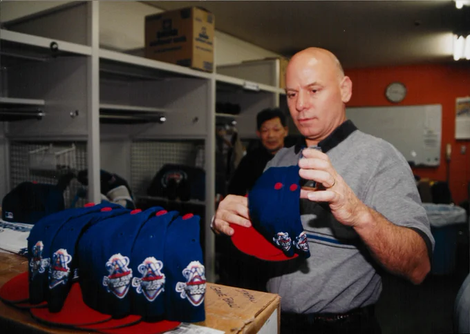 Tom “Otis” Hellmann adjusts hats in the locker room.