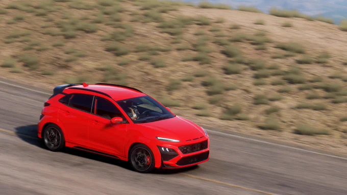 A 2022 Hyundai Kona N finished in my interpretation of Ignite Flame speeding along the hills leading downhill from Le Gran Caldera in Forza Horizon 5.