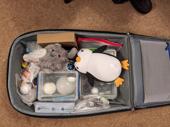 A suitcase with various items including a fluffy comet and a soft penguin 