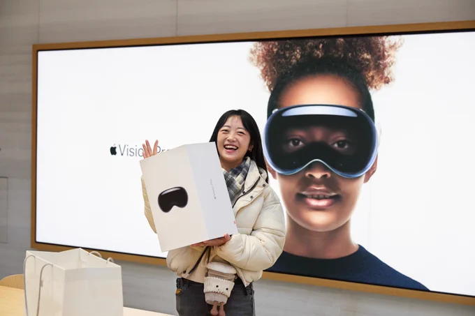 A customer holding up her Apple Vision Pro and smiling.