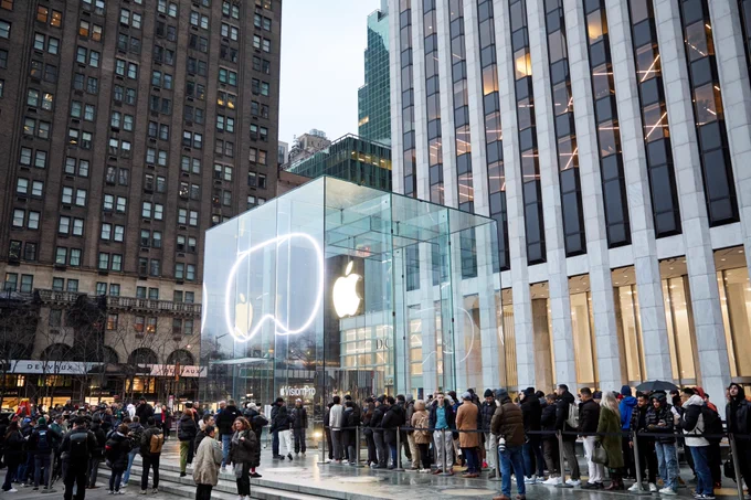 Apple Fifth Avenue, lit up with an outline of Apple Vision Pro, with a crowd waiting to enter.