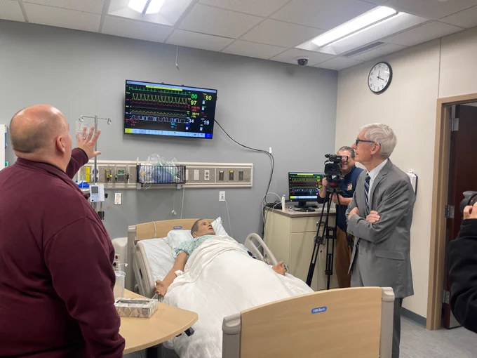Gov. Evers looks at a screen with health vitals during a tour of a healthcare simulation classroom.