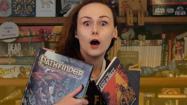 A thumbnail for a video. Dael in front of a bookshelf holding several TTRPG rule books.