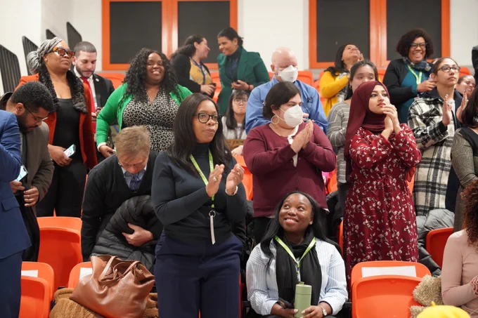 Group of people, including Chair of the NYC Council Committee on Education, Rita Joseph, clapping inside of PS 958 for a Special Education Announcement.