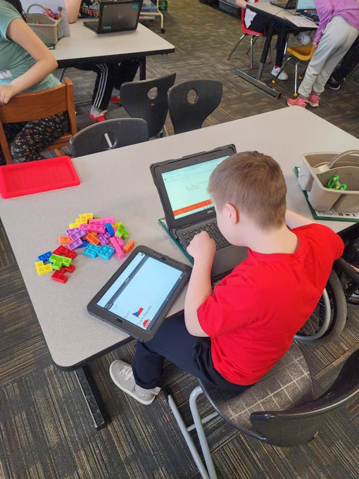 Student using communication device, and predictive text on chromebook to write a story.