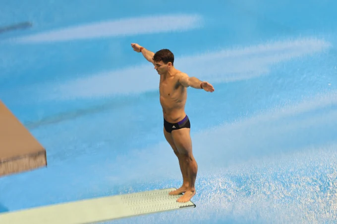 Ross Haslam stands ready to dive at the end of the 1m springboard, arms out wide