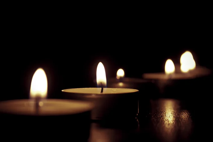A photo of several lit tea lights in a row