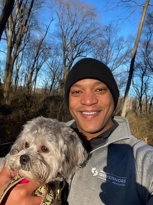 Governor Moore smiling and holding Tucker in one hand at Tuckahoe State Park.