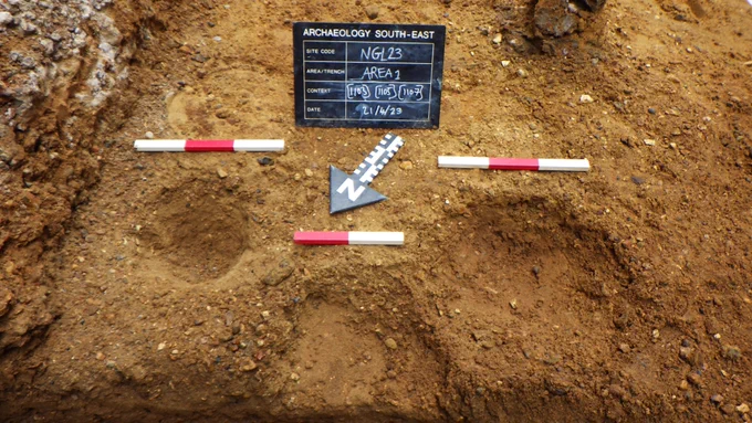 Three excavated post holes looking like shallow pits dug in the ground on an archaeological site, each roughly 20cm in diameter but one is much larger >30cm. @ArchSouthEast 