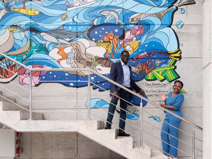 Two people standing on stairs in front of a large painting
