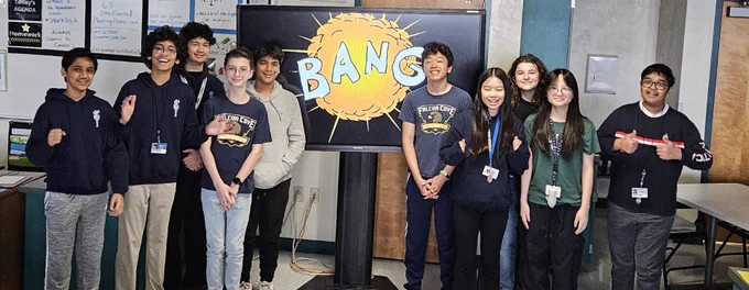 A group of students in a classroom in front of a TV with a logo reading "Bang."