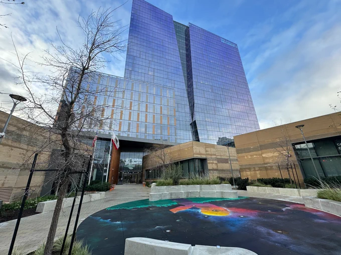A wide photo of from the outside of the CNRA headquarters building showing the ground, building, and cloudy sky.