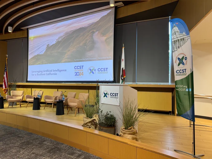 A view of the stage with empty seats and podium, CCST branding, and a title slide up on the screen.