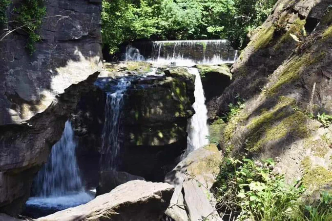 The waterfall at Aberdulais Tinworks. Light flow of water over rocks on a sunny day.