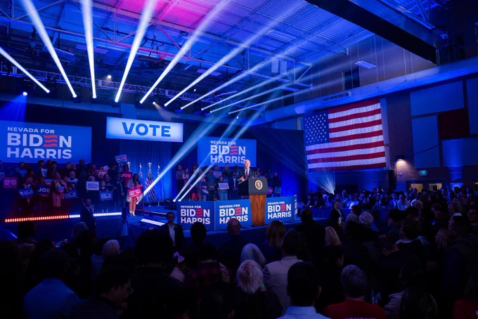President Joe Biden delivering remarks at a rally in Las Vegas, Nevada. Behind him are "Biden Harris" and "Vote" signs.