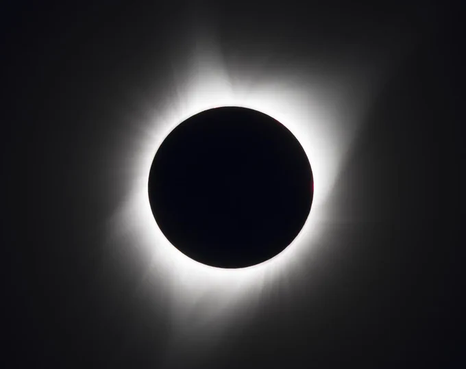A total solar eclipse is seen on Monday, August 21, 2017 above Madras, Oregon. The dark circle formation at the center is the Moon which is blocking the Sun with its white colored rays peeking out from behind the Moon. The darkness of space is surrounding the background. Credit: NASA/Aubrey Gemignani 