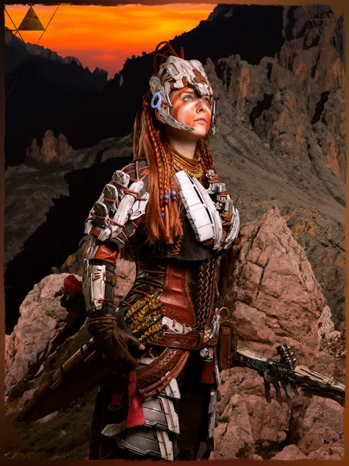 A cosplayer is dressed as Aloy from the Horizon franchise. The backdrop is mountainous.