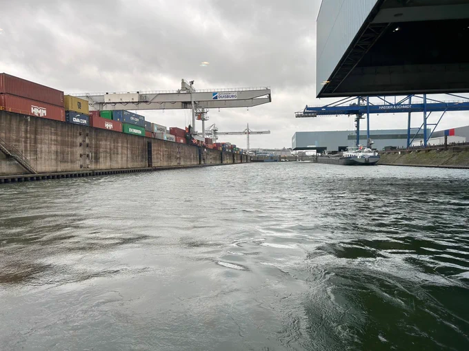 Foto vanaf het water genomen. Aan wal zie je containers