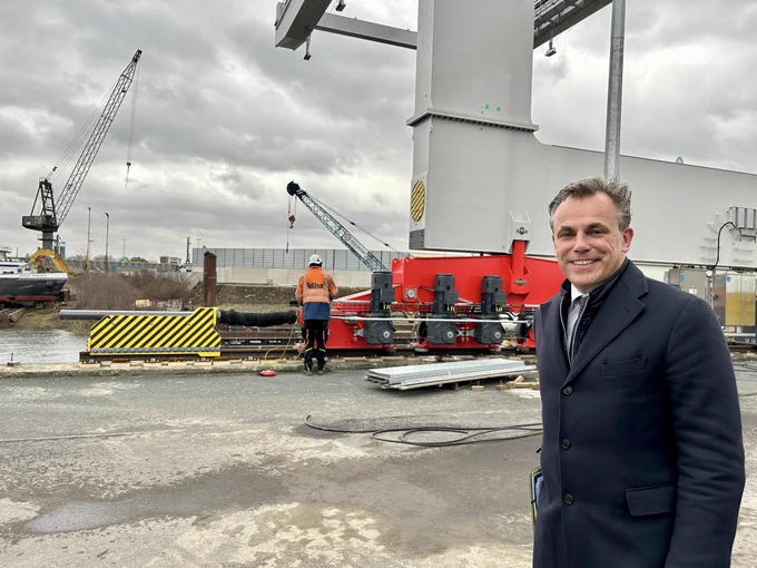 Minister Mark Harbers in het havengebied, op de achtergrond wordt gewerkt..